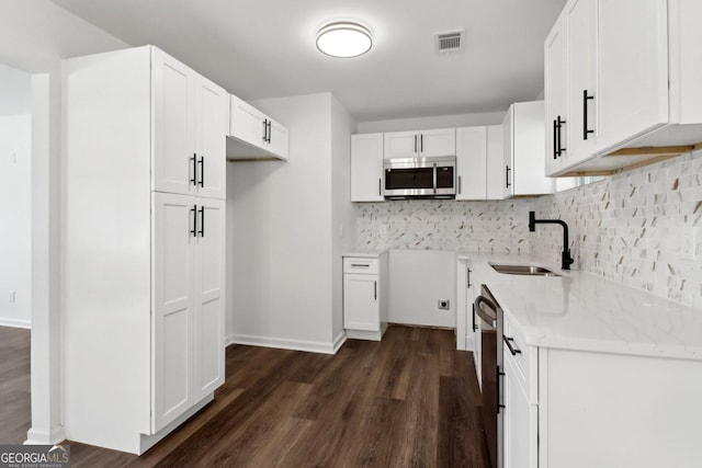 kitchen with sink, dark hardwood / wood-style flooring, white cabinets, stainless steel appliances, and backsplash