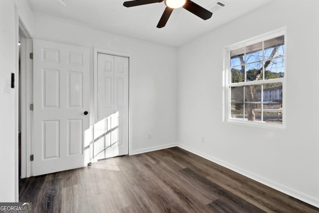 unfurnished bedroom featuring dark wood-type flooring, ceiling fan, and a closet