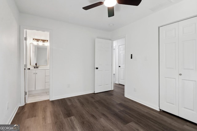 unfurnished bedroom with dark wood-type flooring, ceiling fan, ensuite bathroom, and a closet