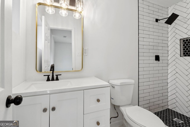 bathroom featuring vanity, toilet, and a tile shower