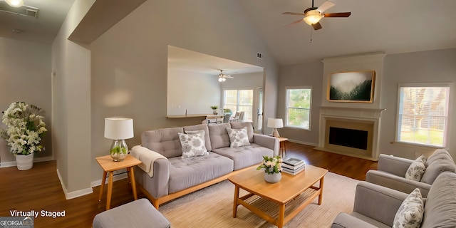 living room featuring hardwood / wood-style flooring, ceiling fan, a large fireplace, and high vaulted ceiling