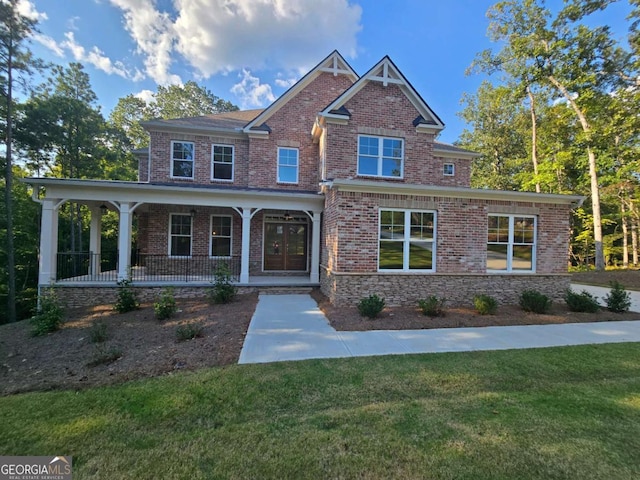 craftsman house with a porch, a front yard, and brick siding