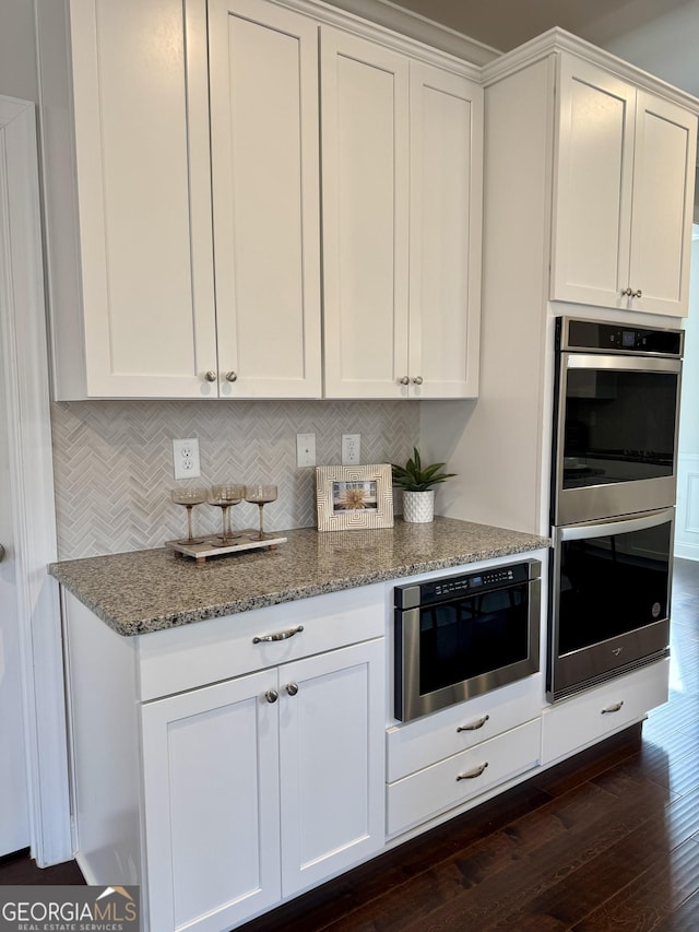 kitchen featuring dark wood-style floors, stainless steel double oven, white cabinets, and light stone countertops