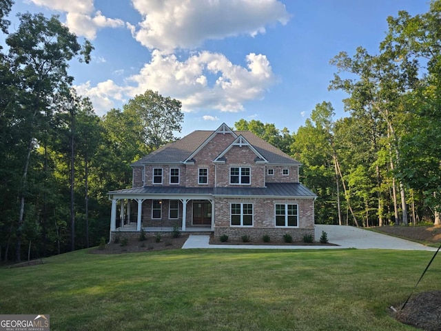 view of front of home featuring metal roof, covered porch, brick siding, a front lawn, and a standing seam roof