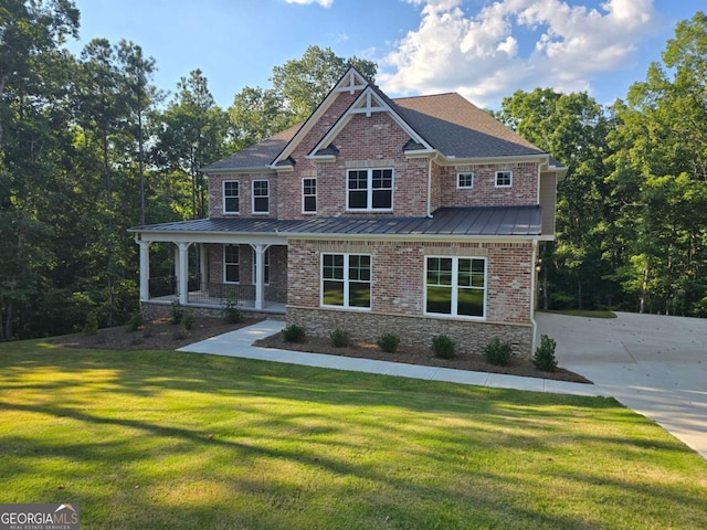 craftsman inspired home featuring metal roof, a standing seam roof, a front yard, a porch, and brick siding