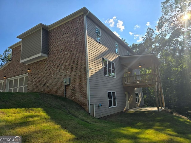 back of property with brick siding, a lawn, and a deck