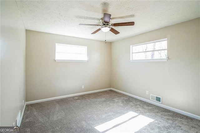 carpeted spare room with ceiling fan and a textured ceiling