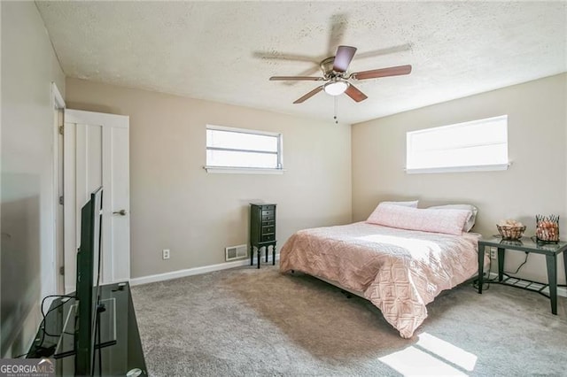 carpeted bedroom with ceiling fan and a textured ceiling