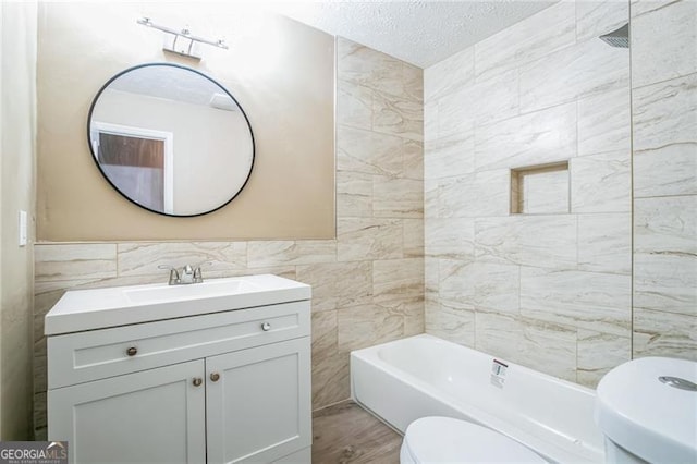 full bathroom with wood-type flooring, tile walls, vanity, toilet, and a textured ceiling