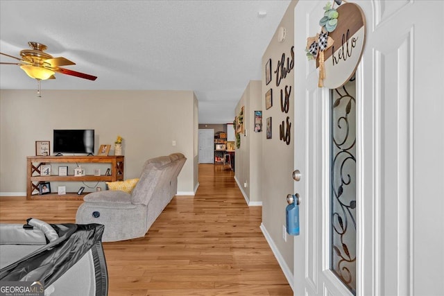 living room with ceiling fan, a textured ceiling, and light hardwood / wood-style floors