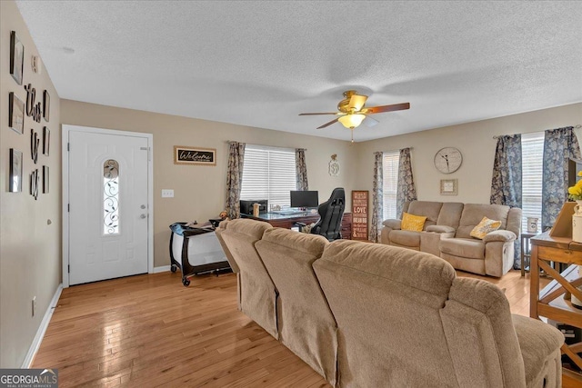 living room with ceiling fan, plenty of natural light, a textured ceiling, and light hardwood / wood-style floors