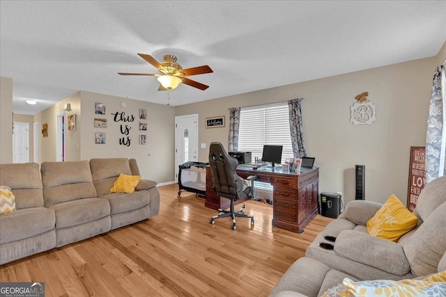 home office featuring ceiling fan, light hardwood / wood-style floors, and a textured ceiling