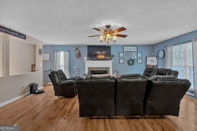 living room featuring ceiling fan, a textured ceiling, and light wood-type flooring