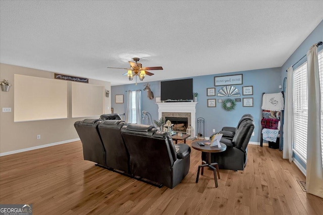 living room featuring ceiling fan, light hardwood / wood-style floors, and a textured ceiling