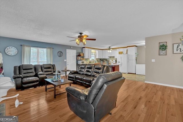 living room with ceiling fan, light hardwood / wood-style flooring, and a textured ceiling