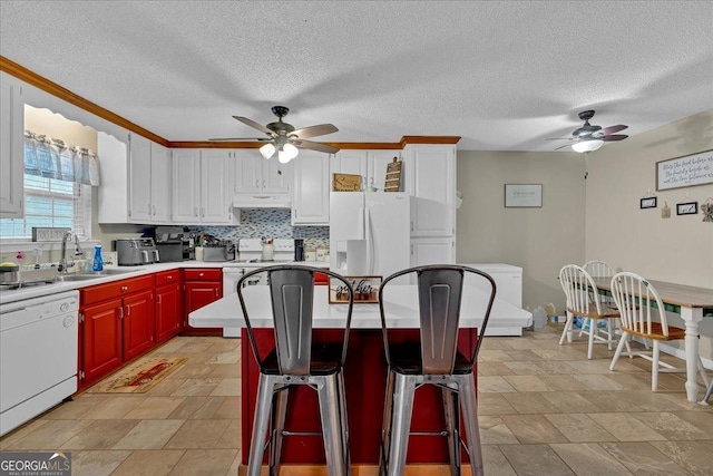 kitchen featuring sink, backsplash, white cabinets, and white appliances