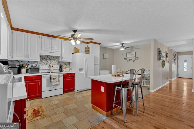 kitchen featuring white appliances, a breakfast bar area, tasteful backsplash, white cabinets, and a kitchen island