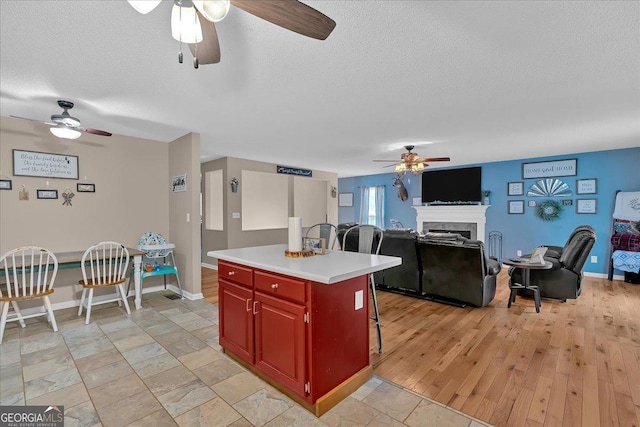 kitchen with a kitchen island, light wood-type flooring, a textured ceiling, and a kitchen breakfast bar