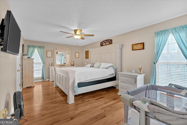 bedroom with multiple windows, ceiling fan, light hardwood / wood-style floors, and a textured ceiling