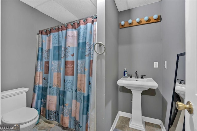 bathroom with a paneled ceiling, toilet, and walk in shower