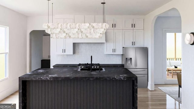 kitchen featuring white cabinetry, pendant lighting, an island with sink, and stainless steel refrigerator with ice dispenser