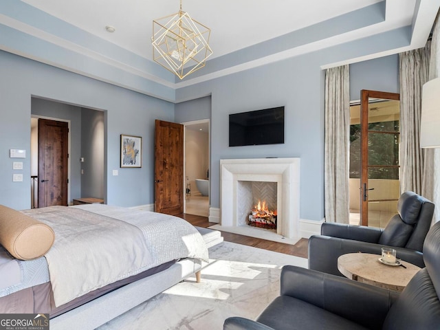 1500 W Wesley Rd NW, Atlanta, GA 30327 - bedroom featuring a fireplace with flush hearth, a tray ceiling, wood finished floors, and a chandelier