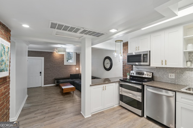 kitchen featuring white cabinetry, brick wall, and appliances with stainless steel finishes