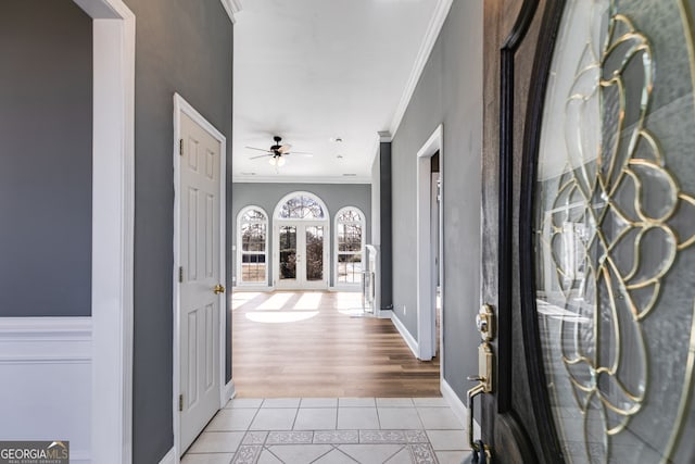 tiled foyer entrance with crown molding and ceiling fan