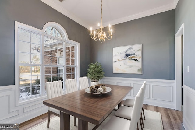 dining room featuring hardwood / wood-style flooring, ornamental molding, and an inviting chandelier