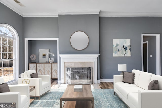living room featuring hardwood / wood-style floors, a high end fireplace, plenty of natural light, and ornamental molding