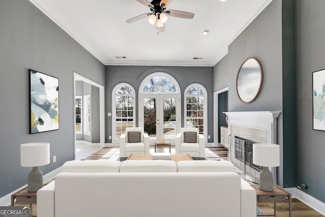 living room with crown molding, ceiling fan, a premium fireplace, and french doors