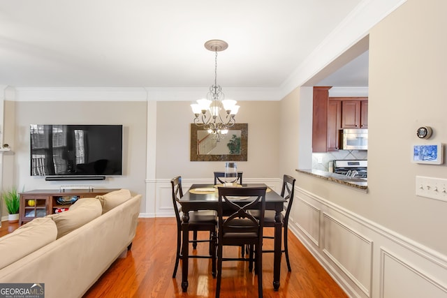 dining room featuring crown molding, wood-type flooring, and a notable chandelier