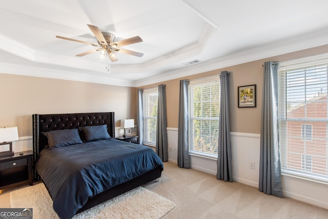 carpeted bedroom featuring ceiling fan, ornamental molding, a raised ceiling, and multiple windows