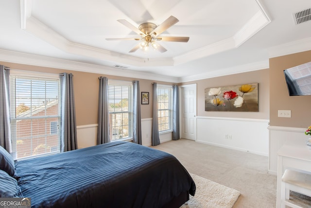 carpeted bedroom with crown molding, ceiling fan, and a raised ceiling