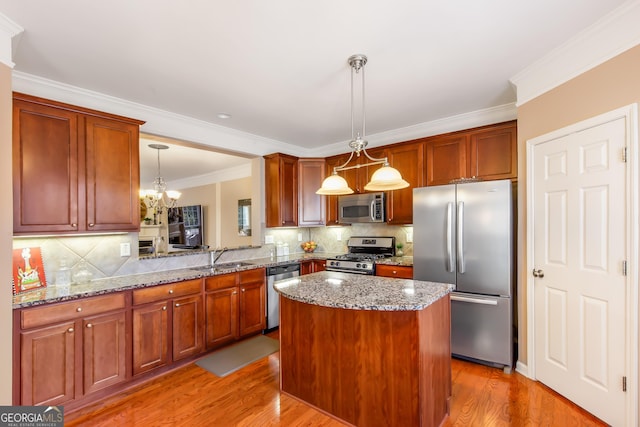 kitchen with appliances with stainless steel finishes, decorative light fixtures, kitchen peninsula, and decorative backsplash