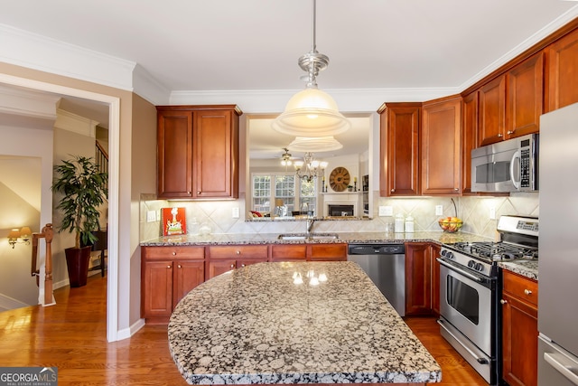 kitchen featuring sink, hanging light fixtures, ornamental molding, appliances with stainless steel finishes, and backsplash