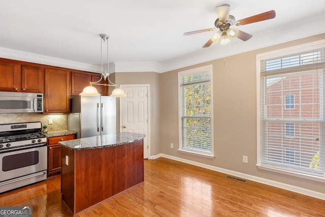 kitchen featuring stainless steel appliances, a center island, ornamental molding, decorative backsplash, and decorative light fixtures