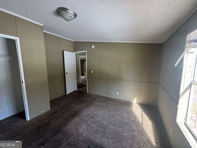 unfurnished bedroom featuring a closet, dark carpet, and a textured ceiling