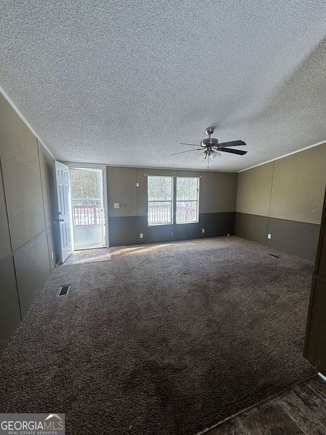 carpeted empty room with ceiling fan and a textured ceiling