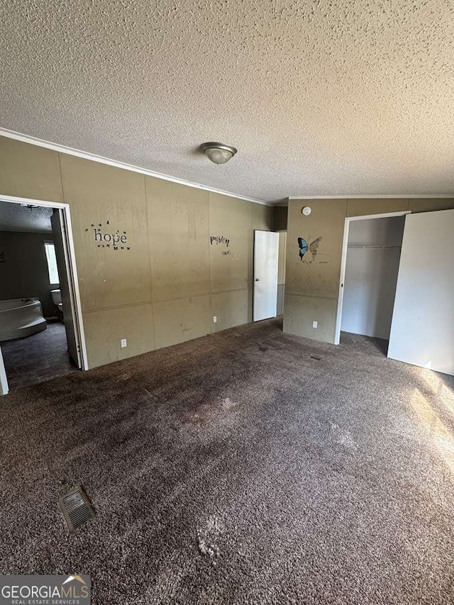 interior space featuring a closet, a textured ceiling, and dark colored carpet