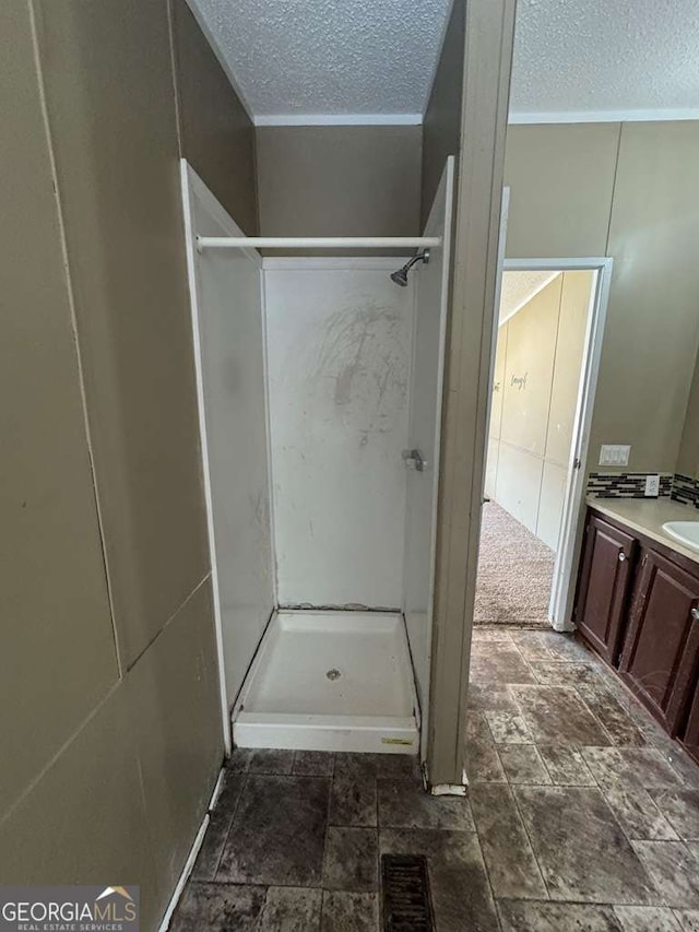 bathroom with walk in shower, vanity, and a textured ceiling