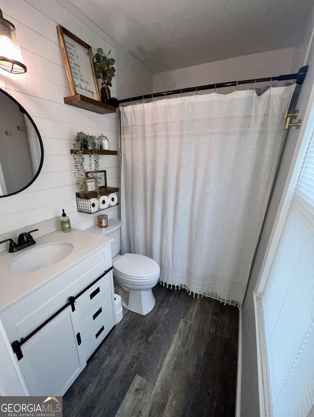 bathroom with hardwood / wood-style flooring, vanity, toilet, and wood walls