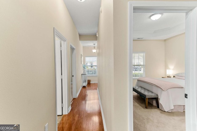 hallway featuring a raised ceiling, crown molding, and hardwood / wood-style flooring