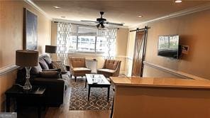 living room with hardwood / wood-style flooring, ornamental molding, a barn door, and ceiling fan