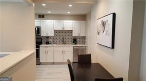 kitchen featuring tasteful backsplash, appliances with stainless steel finishes, white cabinets, and light wood-type flooring