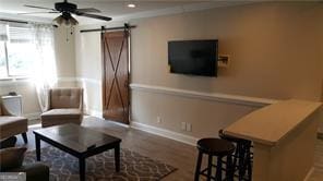 living area featuring ceiling fan, wood-type flooring, and a barn door