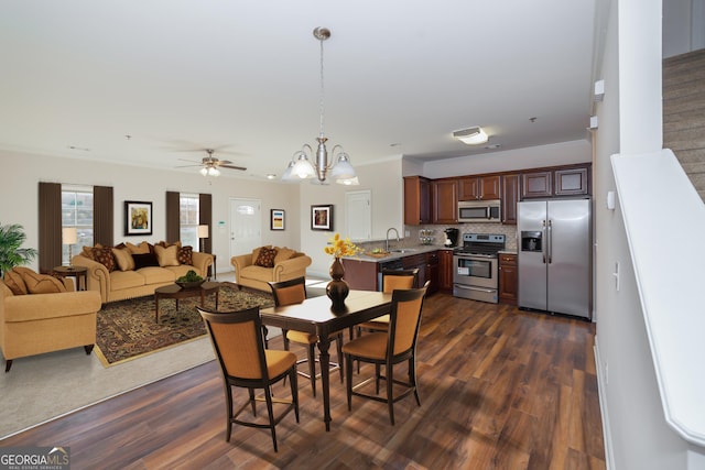 dining room featuring dark hardwood / wood-style flooring, sink, and ceiling fan with notable chandelier