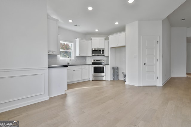 kitchen featuring sink, white cabinetry, backsplash, stainless steel appliances, and light hardwood / wood-style floors