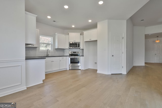 kitchen with sink, white cabinetry, tasteful backsplash, light wood-type flooring, and stainless steel appliances