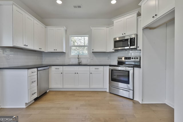 kitchen featuring sink, white cabinetry, light hardwood / wood-style flooring, stainless steel appliances, and decorative backsplash